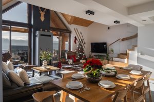 Przytulny salon w stylu chalet z kominkiem i widokiem na Jezioro Czorsztyńskie w apartamencie w Kluszkowcach. Sezonowość w fotografii wnętrz.