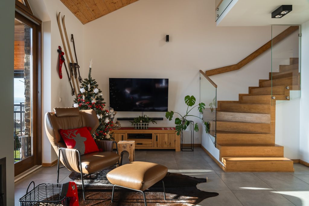 Przytulny salon w stylu chalet z kominkiem i widokiem na Jezioro Czorsztyńskie. Sezonowość w fotografii wnętrz.
